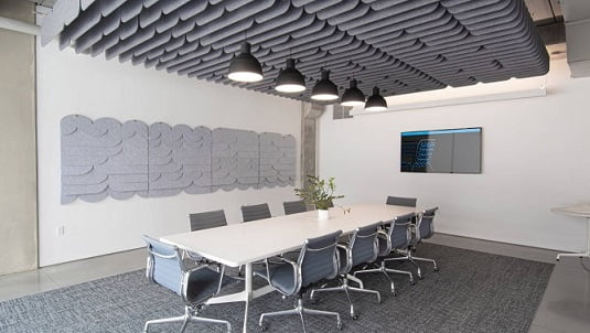 Akoestiek op kantoor met akoestische panelen aan plafond en muur.